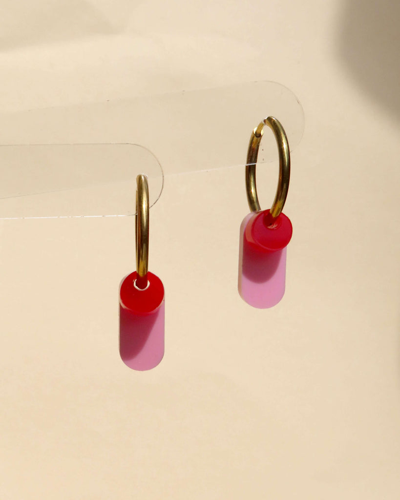Goldfarbene Creolen mit röhrenförmigem rosa Acrylanhänger und rundem roten Element