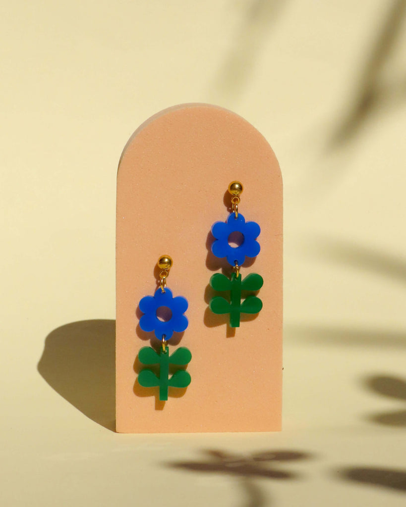 Handgefertigte Blumenohrringe aus Acryl in Blau mit grünem Blattanhänger und vergoldetem Edelstahlstecker