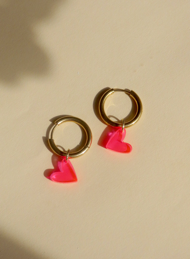 Verspielte Creolen mit transparenten Herzanhängern in Neon Pink und goldglänzendem Edelstahl