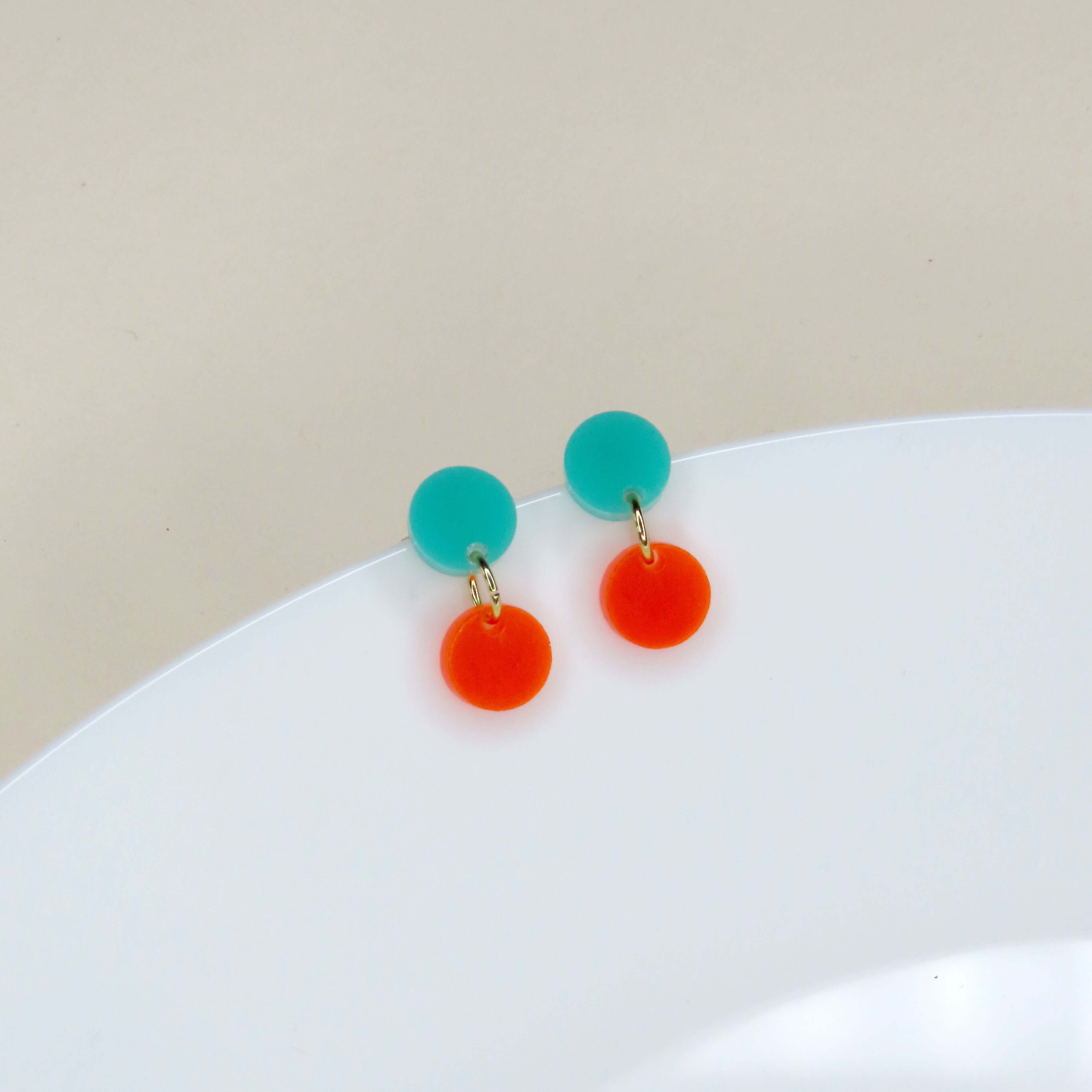 Zwei runde Ohrstecker aus Acryl in Türkis und Neonorange mit goldenen Verbindungselementen
