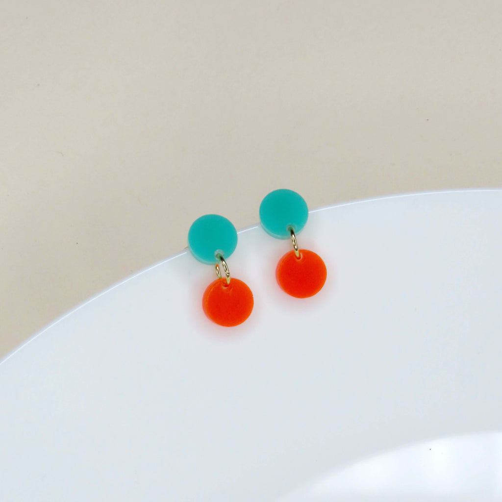 Zwei runde Ohrstecker aus Acryl in Türkis und Neonorange mit goldenen Verbindungselementen