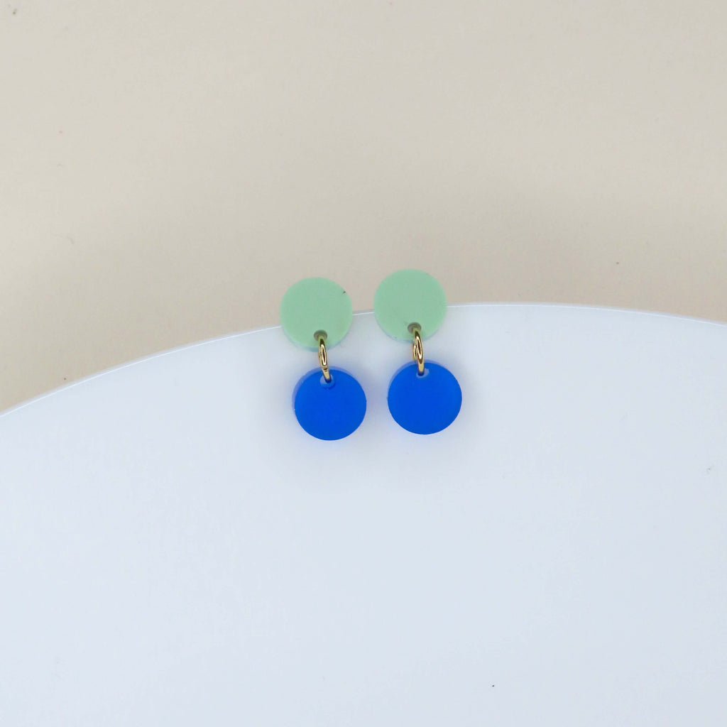 Runde Ohrstecker aus Acryl mit pastellgrünem Stecker und royalblauem Anhänger, verbunden durch goldenen Edelstahlring