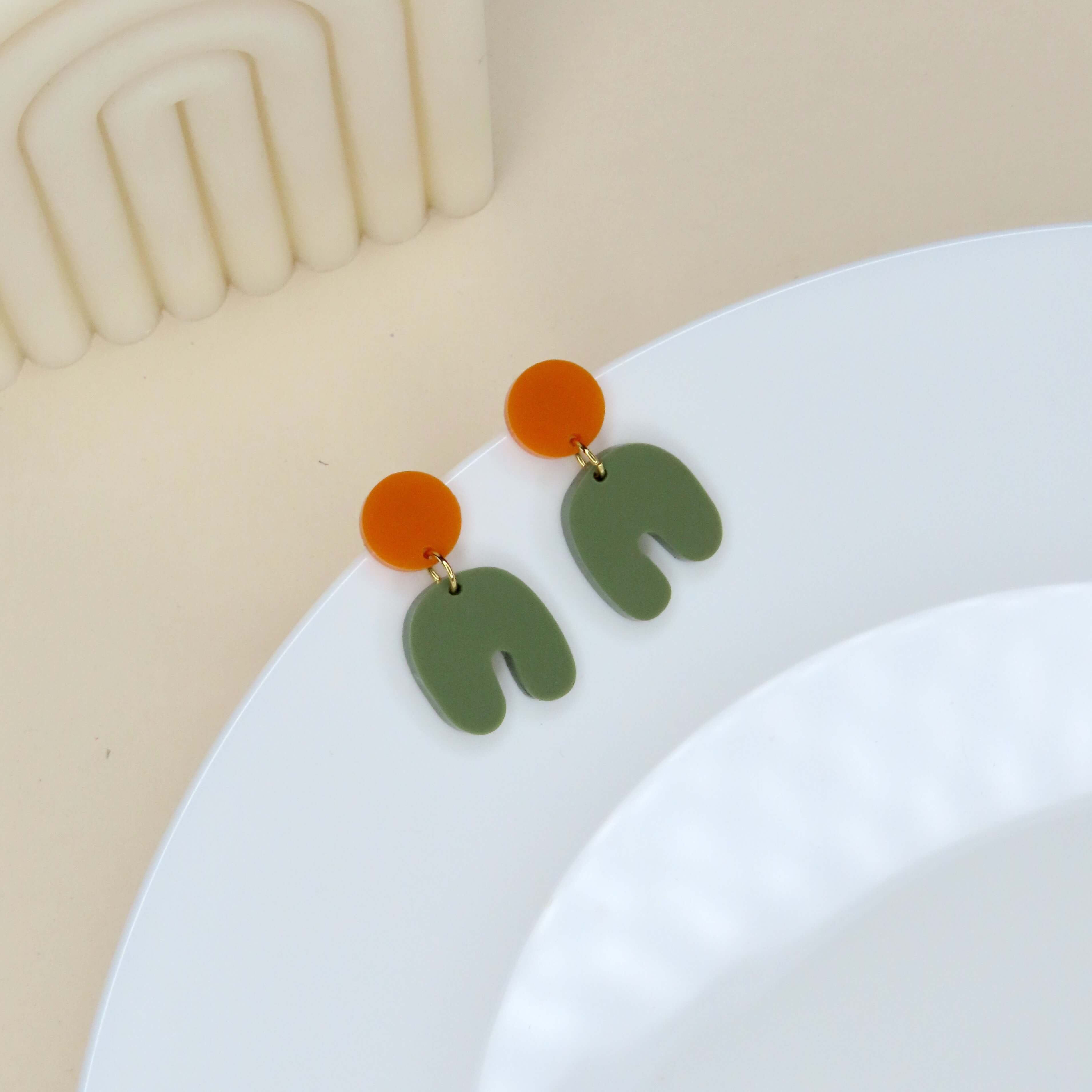 Acryl Ohrringe mit rundem Stecker in kräftigem Orange und bogenförmigem Anhänger in Olivgrün
