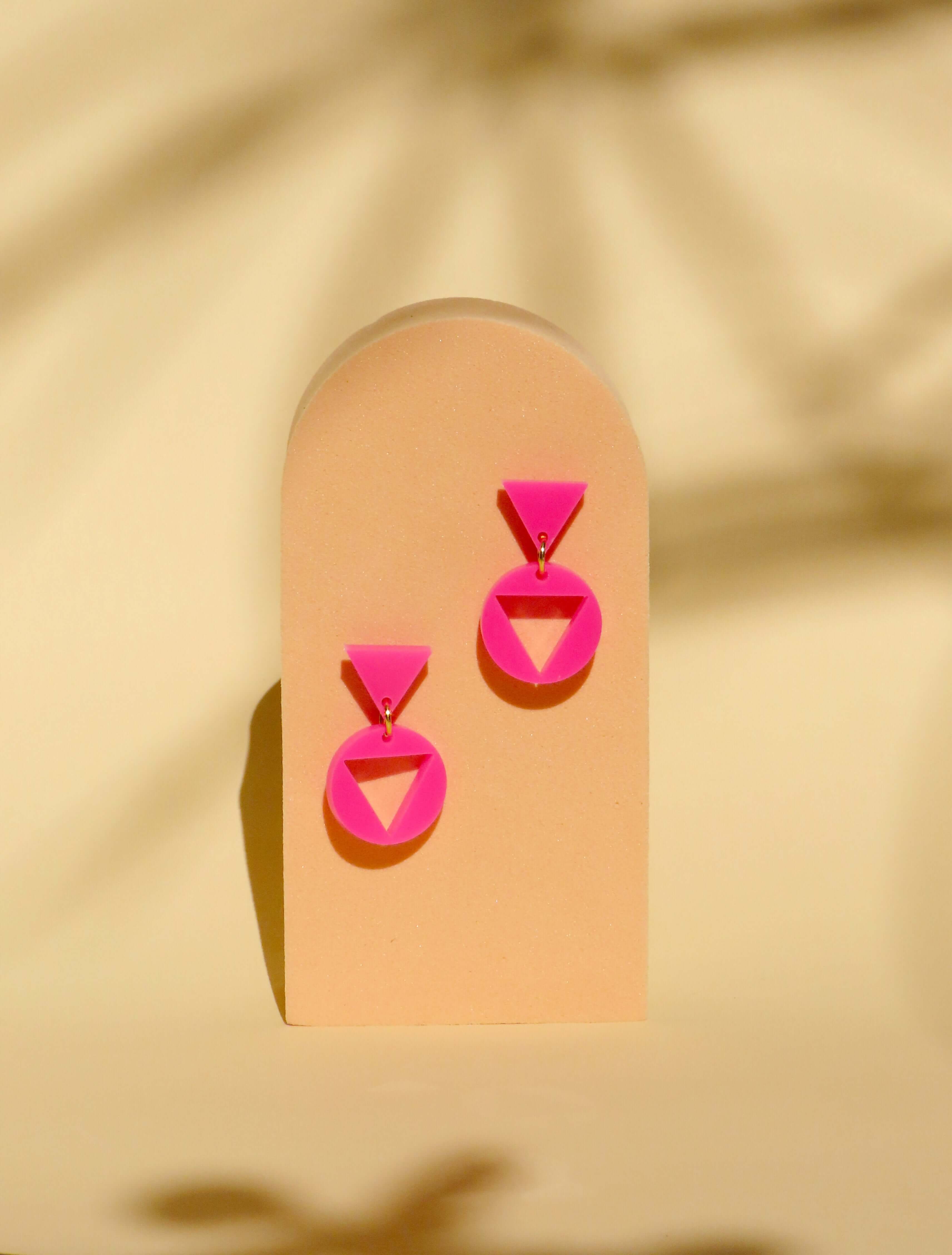 Paar pinke Acryl Ohrhänger mit dreieckigem Stecker und rundem Anhänger, glänzend und deckend gefertigt, verbunden durch goldenes Element
