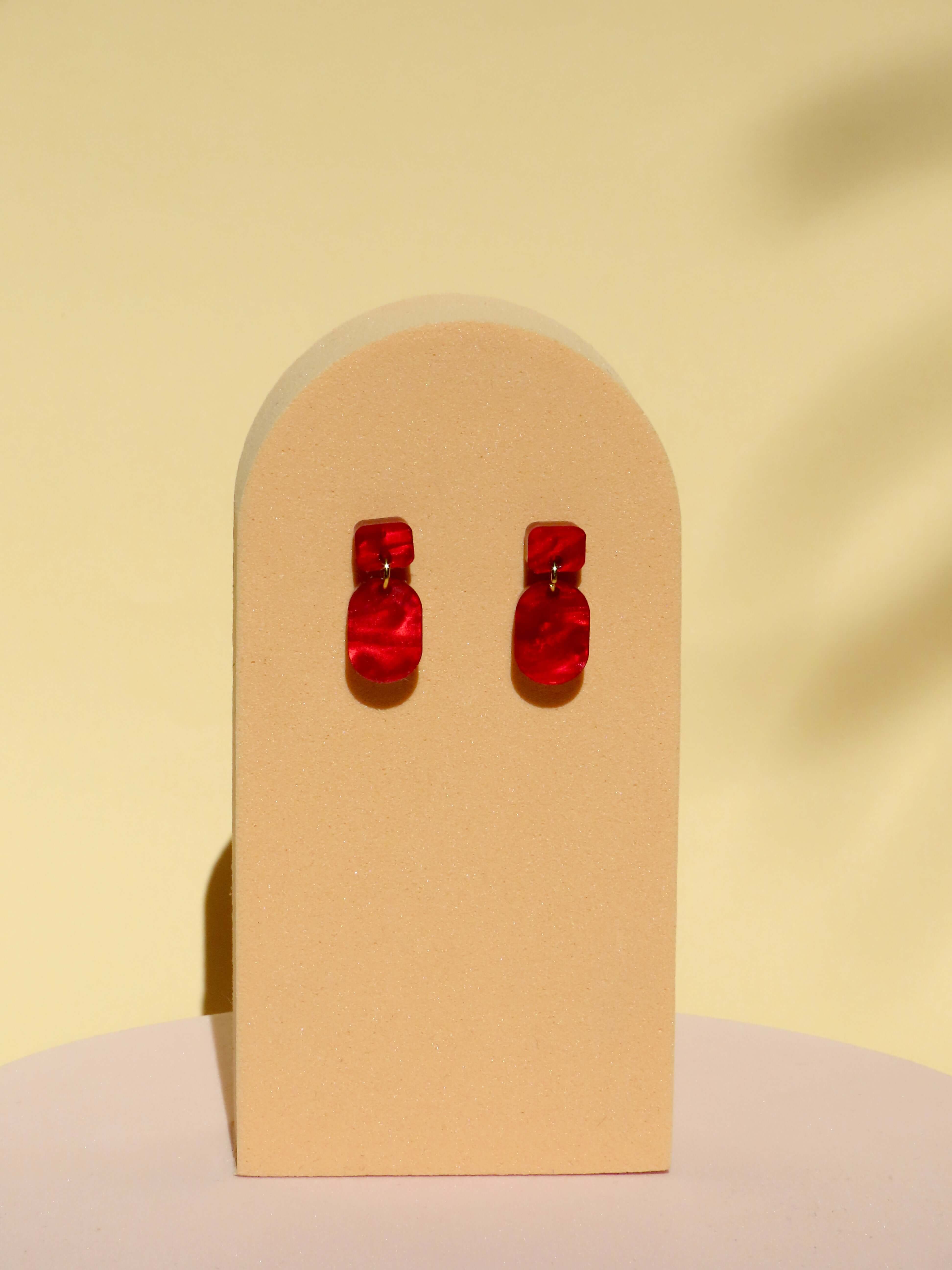 Paar kleiner roter Ohrhänger aus marmoriertem Acryl mit seidig glänzender Oberfläche und goldenem Verbindungselement