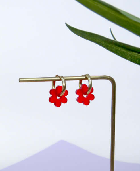 Kleine vergoldete Edelstahl-Creolen mit roten Acryl-Blütenanhängern in stilisierter Form