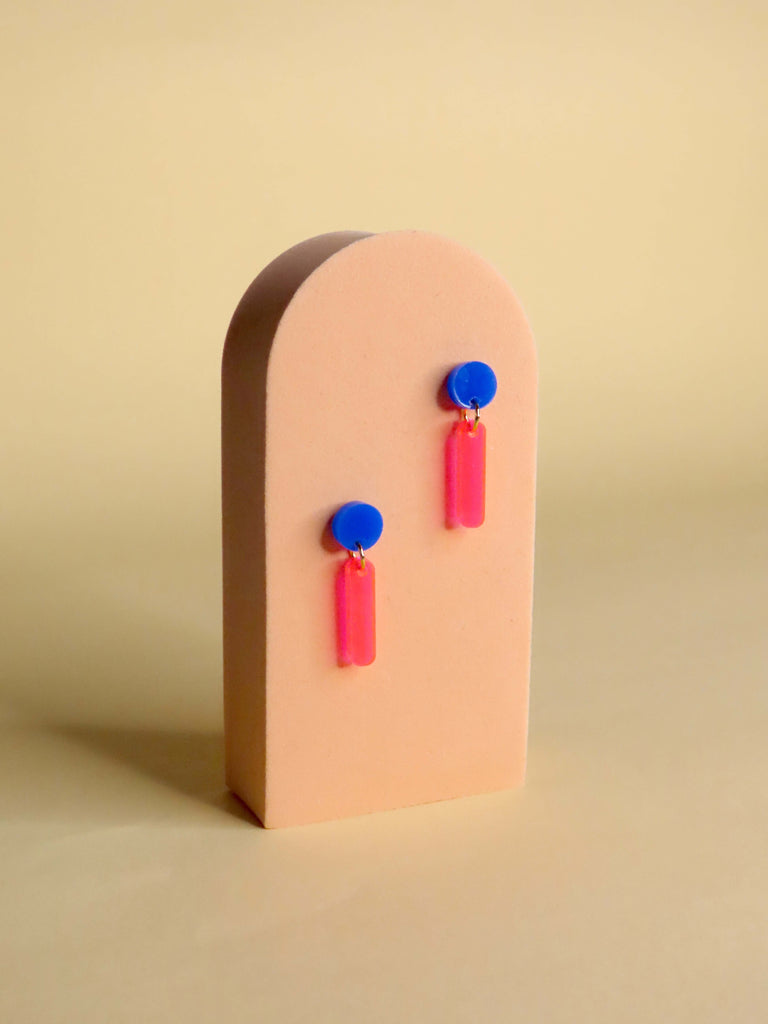 Moderne Acryl-Ohrstecker mit blauem Kreis und neonpinken Rechteckanhängern, verbunden mit Edelstahlösen