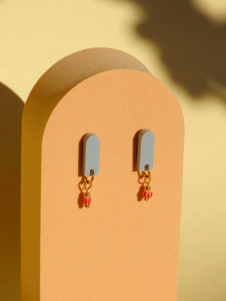 Minimalistische Ohrringe mit salbeigrünem Acryl Stecker, goldfarbenem Verbindungselement und rot gemusterter Perle