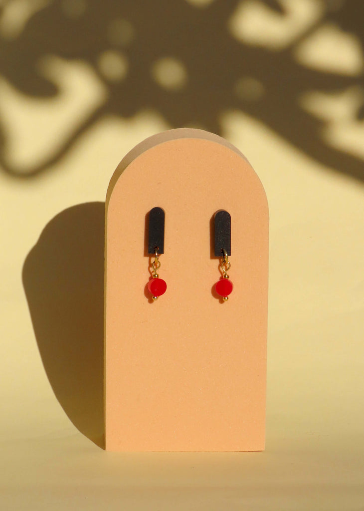 Schwarz Rot Paula Ohrringe, handgemacht aus Acryl und Edelstahl mit roten Akzenten, auf stilvollem Display.