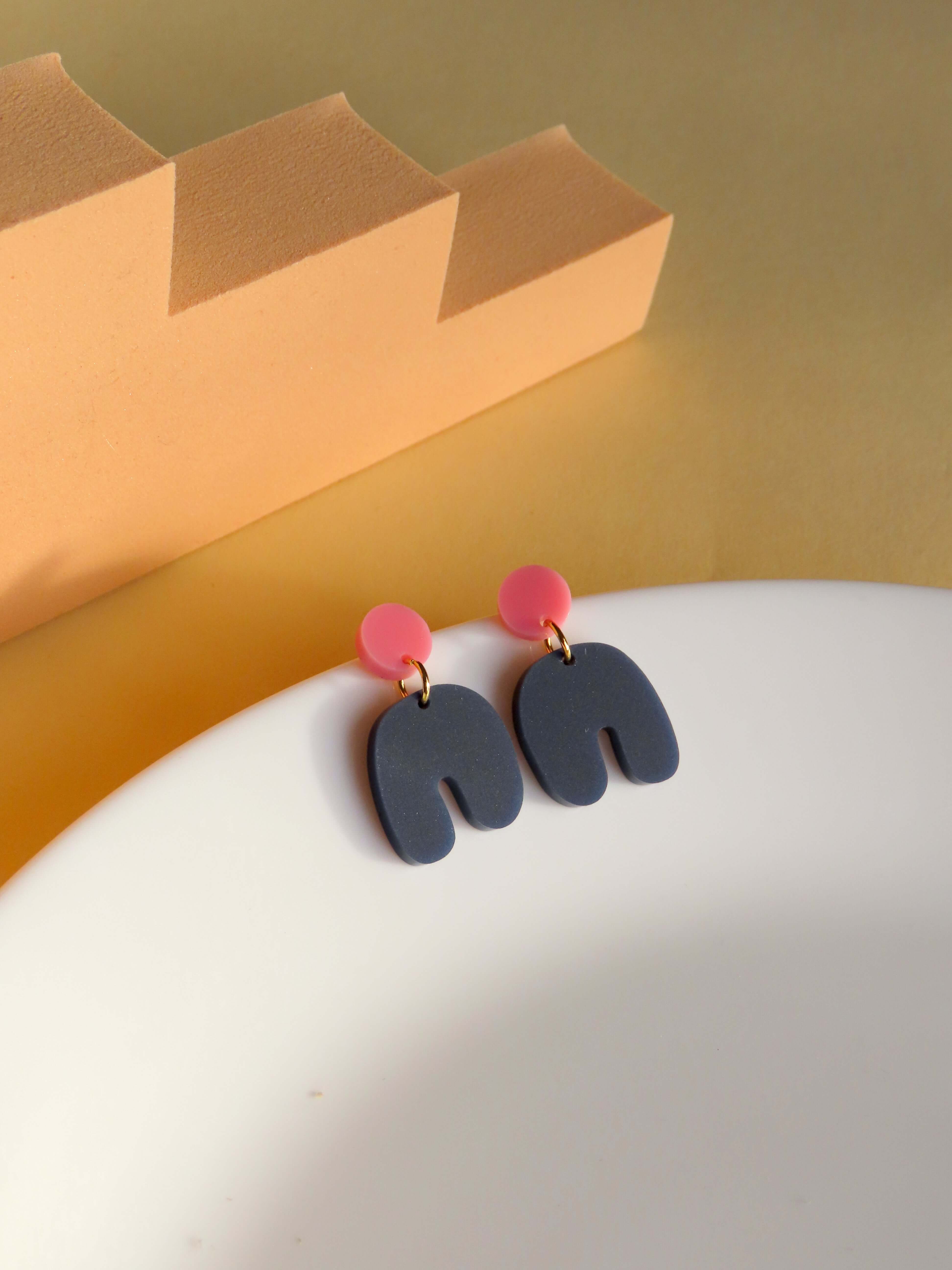 Kleine Squishy Arch Ohrringe aus Acryl in Rosa und Dunkelblau mit runder Steckerform und geschwungenem Bogenanhänger