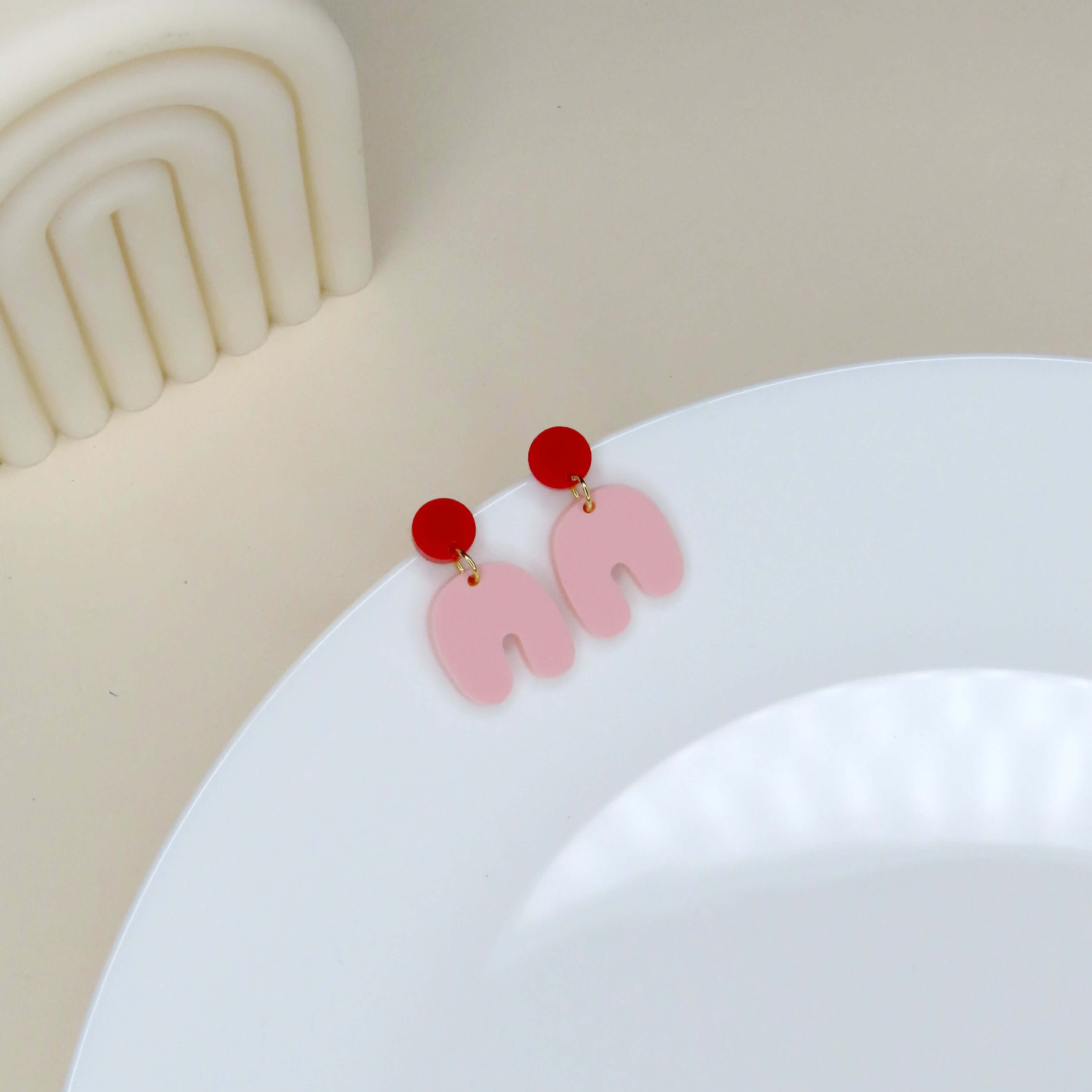 Kleine Squishy Arch Ohrringe aus Acryl in Rot und Hellrosa mit runder Steckerform und bogenförmigem Anhänger