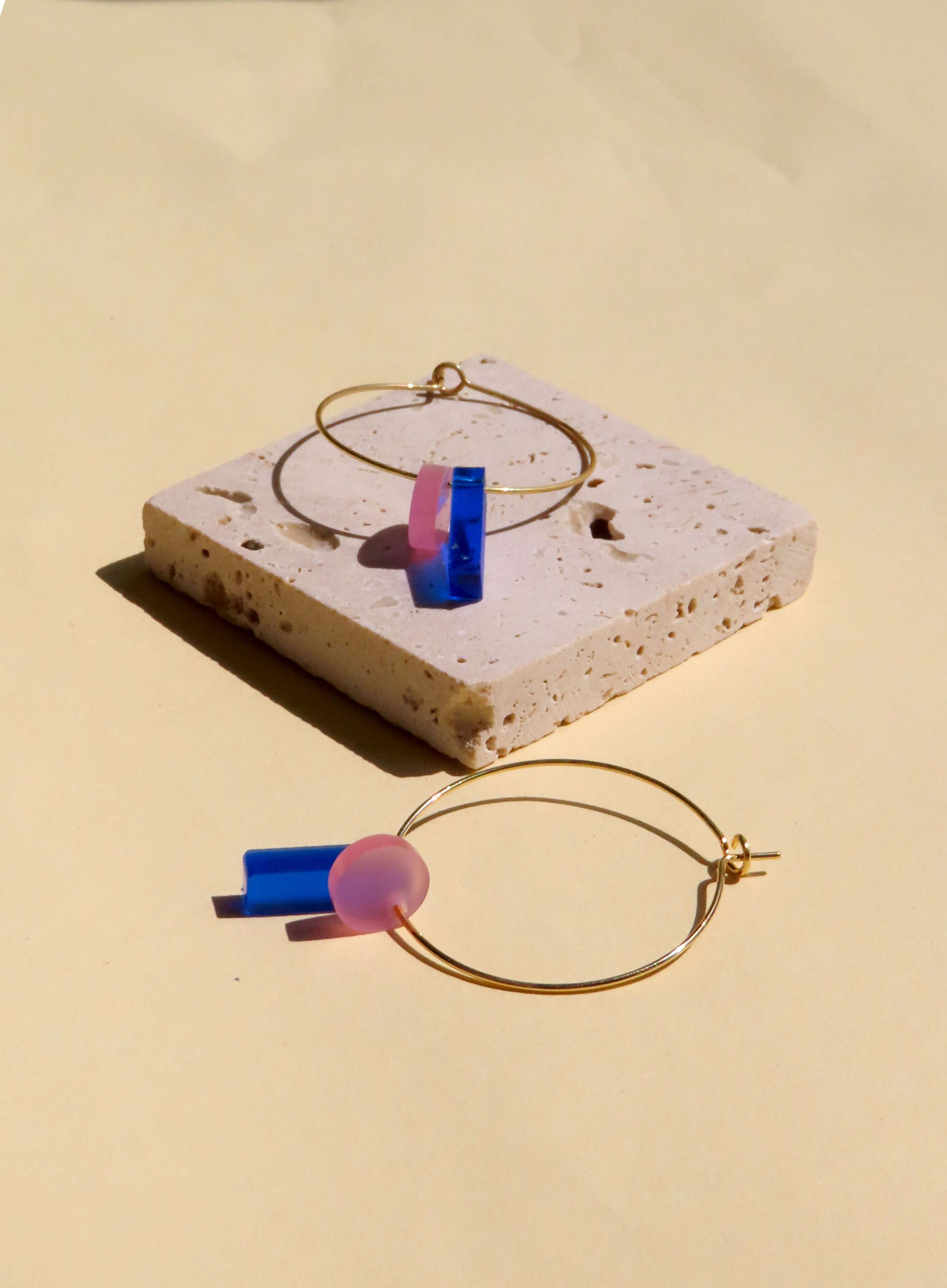moderne creolen-ohrringe mit farbigen anhängern aus kunststoff in blau und rosa
