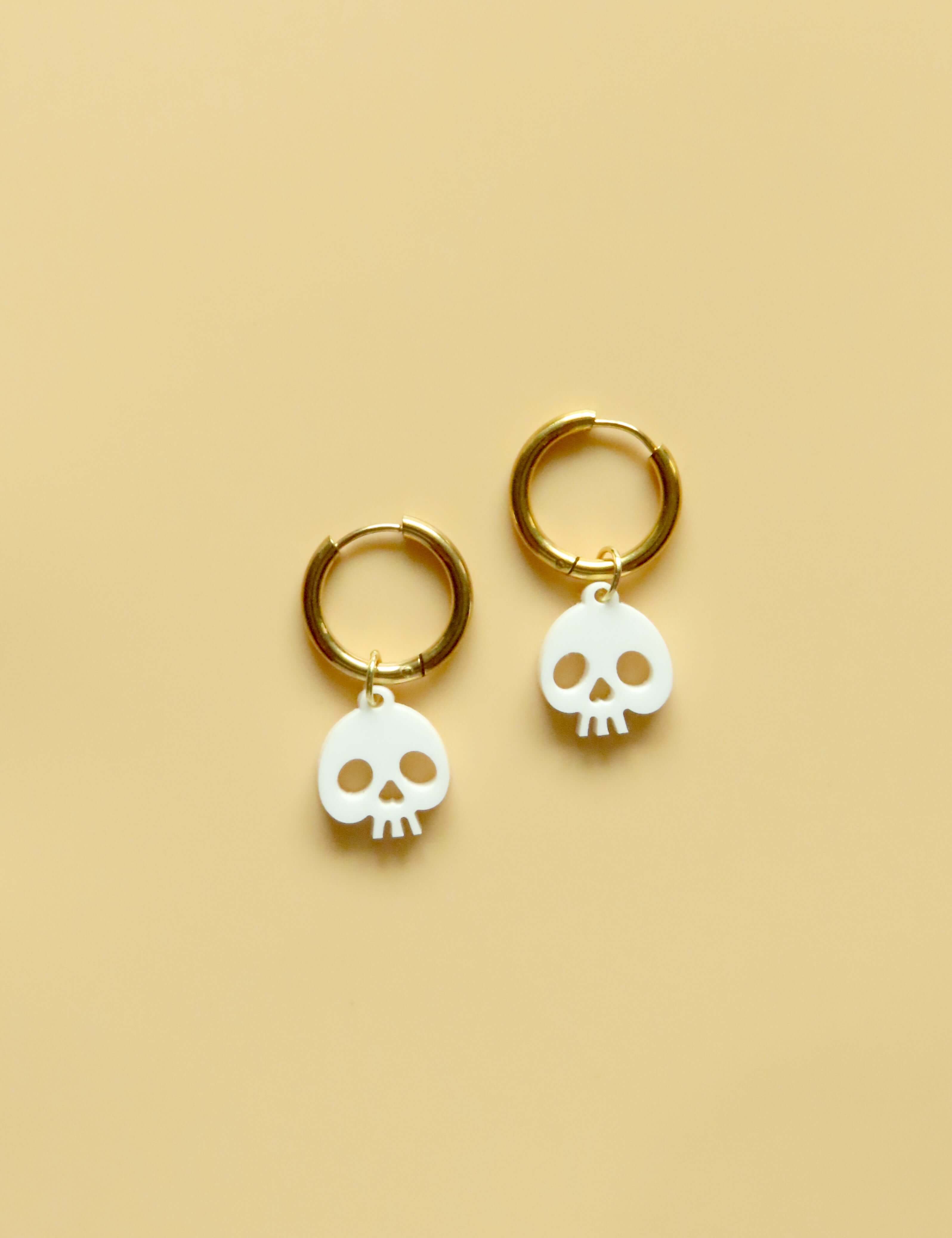 weiße Creolen mit kleinen Acryl-Totenkopf-Anhängern aus glänzendem Weiß und vergoldetem Edelstahl