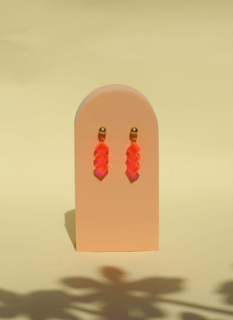 Leichte Ohrhänger aus Acryl in Neon-Pink mit gezackter Zickzack-Form und Edelstahlsteckern