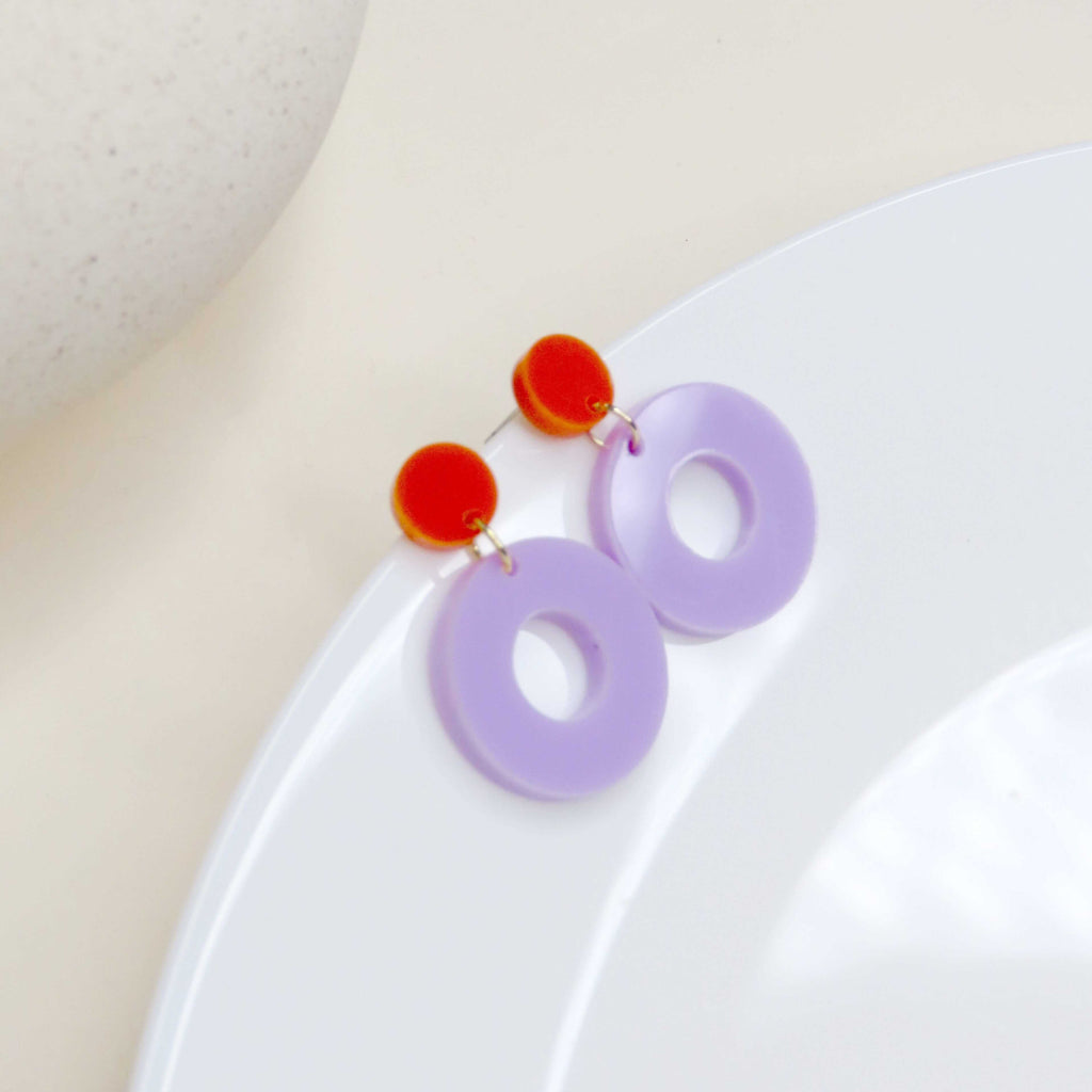 Colorblock Ohrstecker aus glänzendem Acryl in Orange und Flieder, runde Form mit Lochkreis