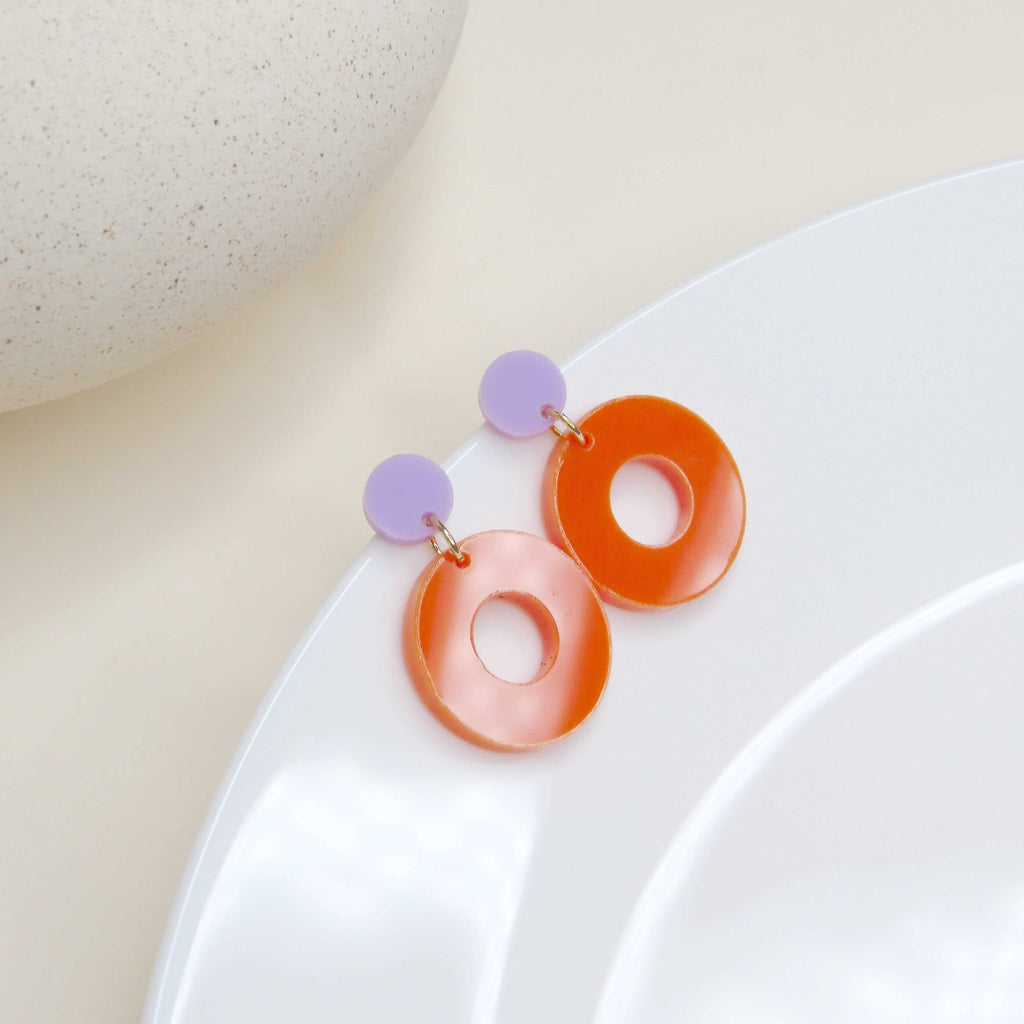 Leichte Ohrringe in Kreis-in-Kreis-Optik mit fliederfarbenem Stecker und großem orangem Acrylring