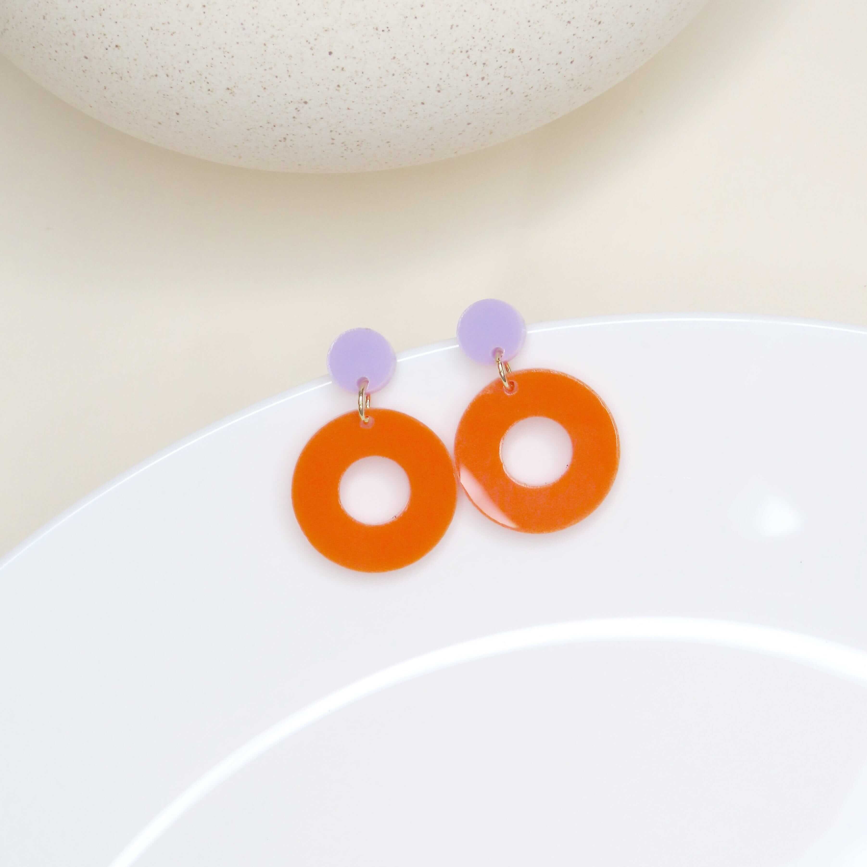Runde Acryl-Ohrringe mit kleinem fliederfarbenem Kreisstecker und großem orangefarbenem Ring mit Loch in der Mitte