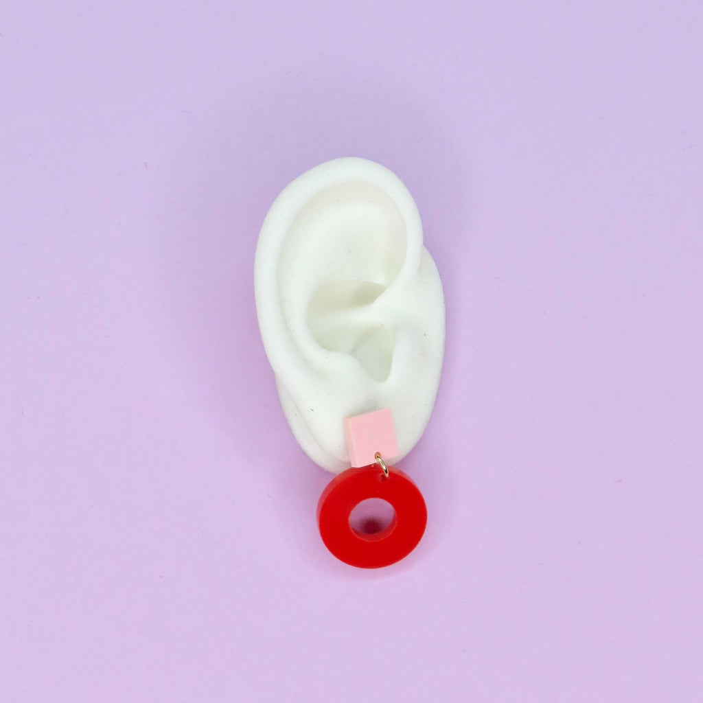 Geometrische Ohrstecker aus glänzendem Acryl mit rosa Quadrat und rotem Kreisanhänger