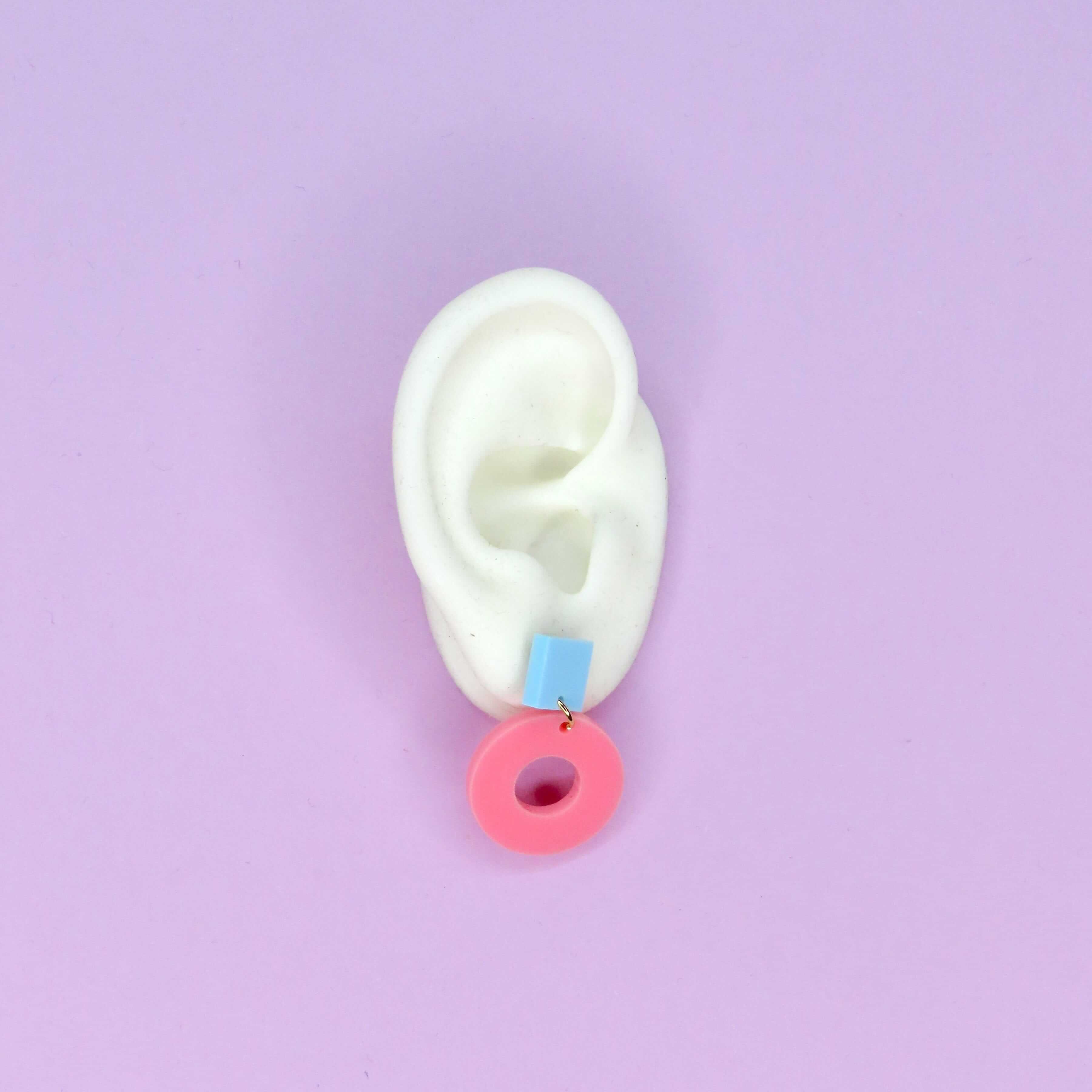 Geometrische Ohrstecker aus Acryl mit hellblauem Quadrat und rosa Kreisring